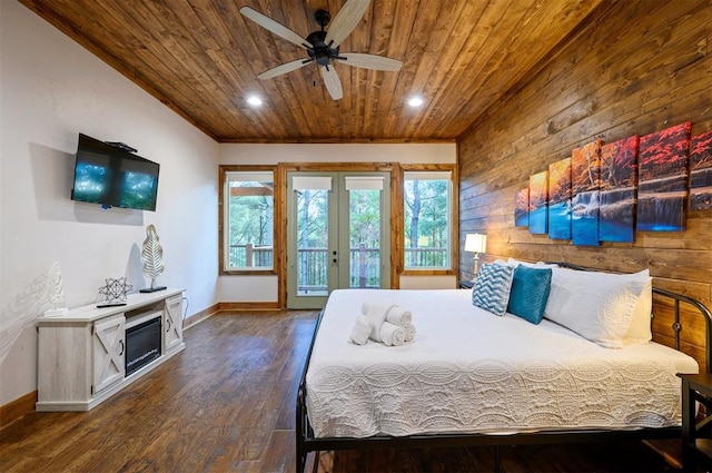 bedroom with access to exterior, ceiling fan, wooden walls, and dark hardwood / wood-style floors