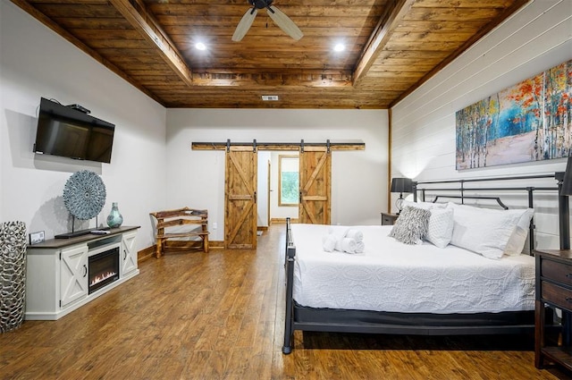 bedroom with wood ceiling, a raised ceiling, ceiling fan, a barn door, and hardwood / wood-style flooring