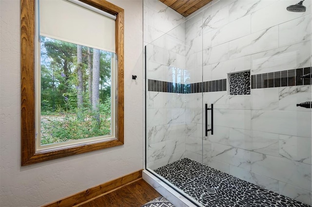 bathroom with wood-type flooring, a shower with door, and a wealth of natural light