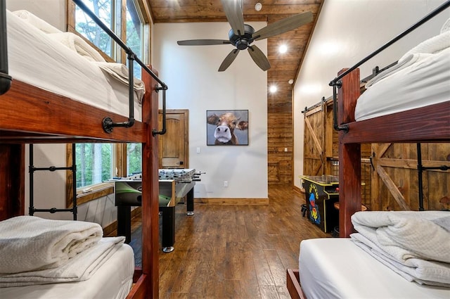 bedroom featuring a barn door, multiple windows, dark wood-type flooring, and ceiling fan