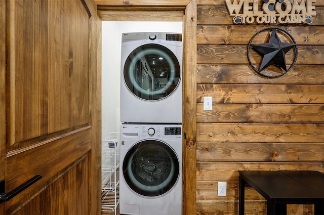 laundry area with wooden walls and stacked washing maching and dryer