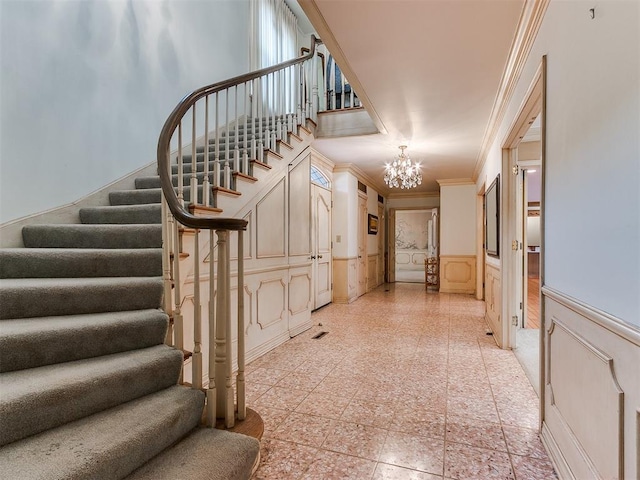 staircase with ornamental molding and a chandelier