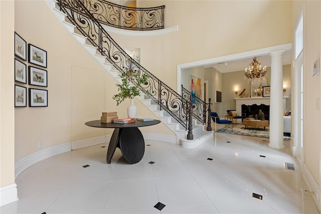 entrance foyer featuring a towering ceiling, light tile patterned floors, and ornate columns