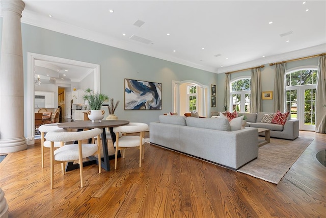 living room with light wood-type flooring, ornamental molding, and decorative columns