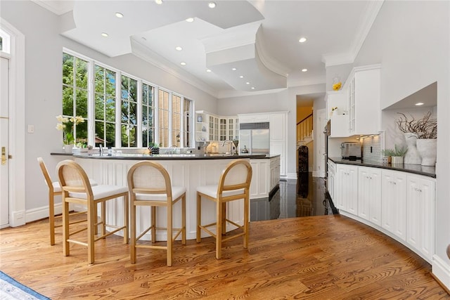 kitchen with built in fridge, crown molding, white cabinets, and light wood-type flooring