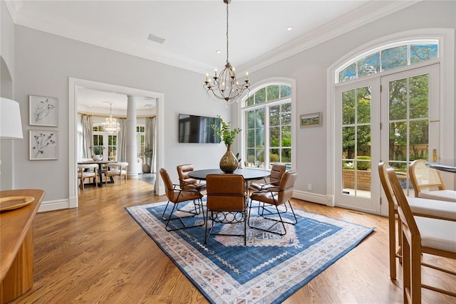 dining space with ornamental molding, a healthy amount of sunlight, a notable chandelier, and light wood-type flooring