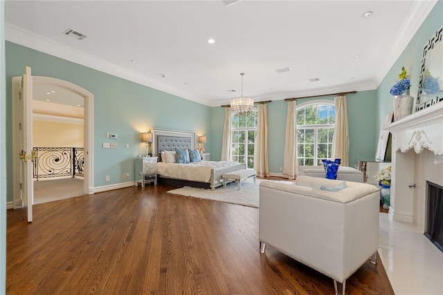 bedroom with a fireplace, an inviting chandelier, dark wood-type flooring, and ornamental molding