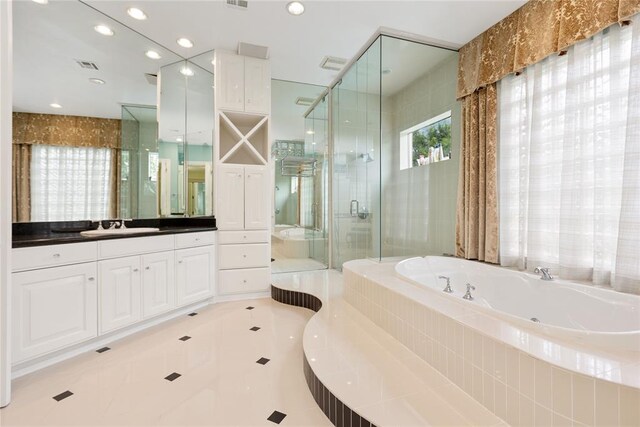 bathroom featuring tile patterned flooring, vanity, and shower with separate bathtub