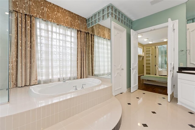 bathroom featuring vanity, tile patterned floors, and tiled tub