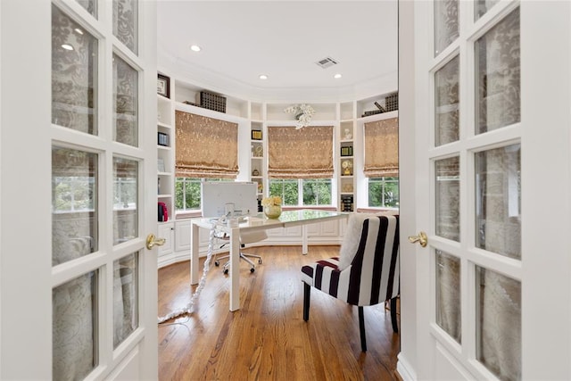 office area with hardwood / wood-style floors, a towering ceiling, built in features, and french doors