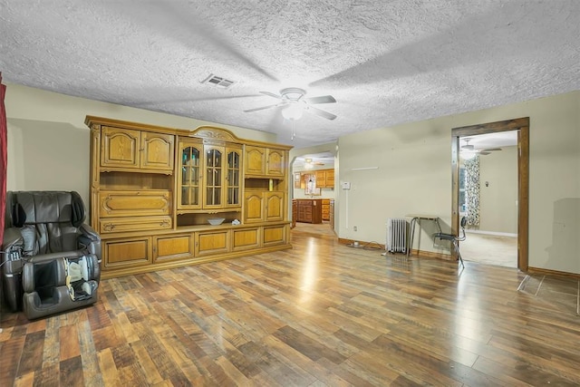 living room featuring radiator heating unit, a textured ceiling, and hardwood / wood-style flooring