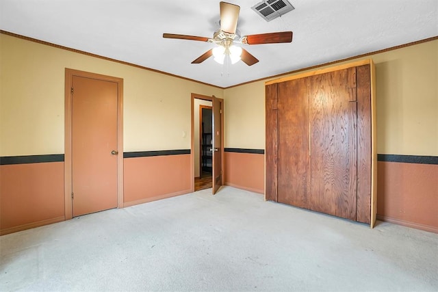 unfurnished bedroom with ceiling fan, crown molding, and light colored carpet