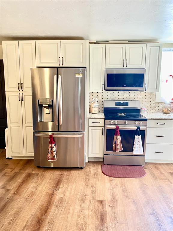 kitchen featuring white cabinets, stainless steel appliances, tasteful backsplash, and light hardwood / wood-style floors