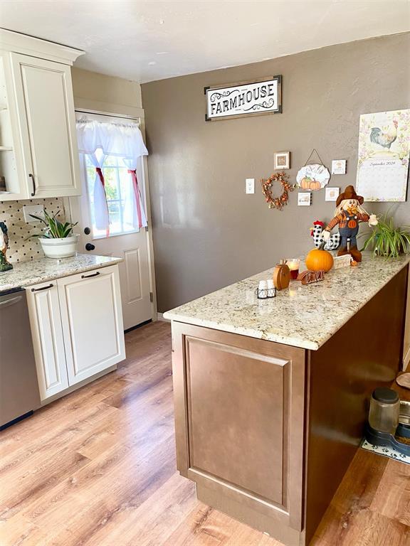 kitchen featuring dishwasher, decorative backsplash, light hardwood / wood-style floors, and light stone counters