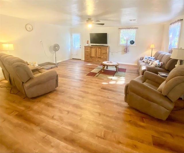 living room with ceiling fan, plenty of natural light, and light wood-type flooring