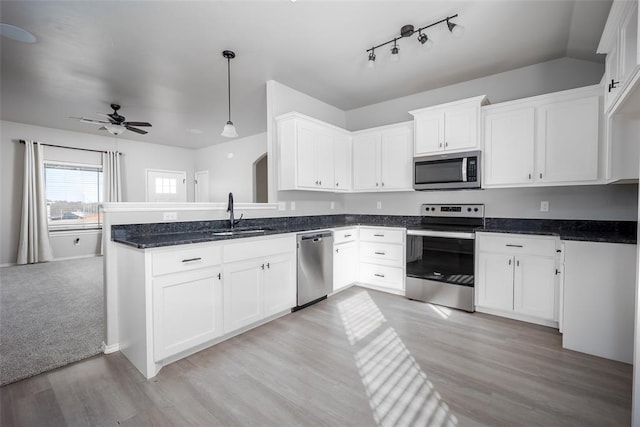 kitchen with decorative light fixtures, sink, white cabinets, kitchen peninsula, and stainless steel appliances