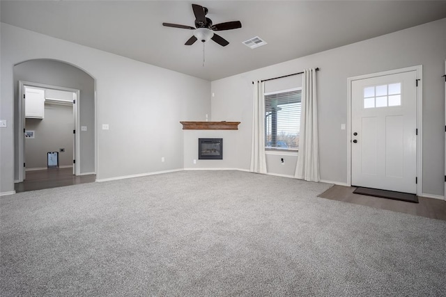 unfurnished living room with ceiling fan and dark carpet