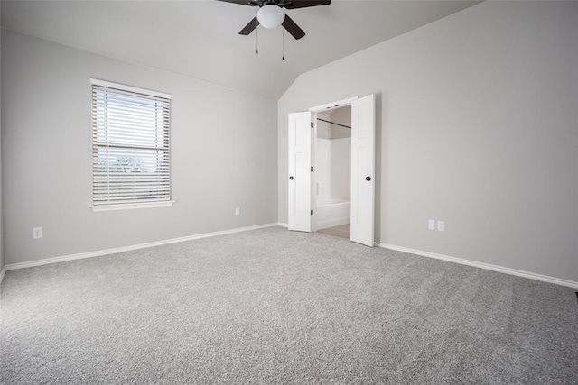 unfurnished bedroom featuring ensuite bath, vaulted ceiling, ceiling fan, and carpet