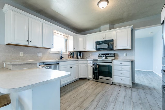 kitchen with sink, stainless steel appliances, light hardwood / wood-style flooring, kitchen peninsula, and white cabinets