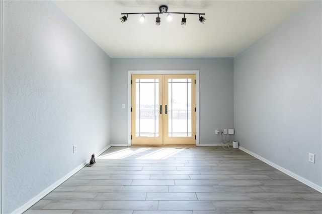 spare room with track lighting, light hardwood / wood-style flooring, and french doors