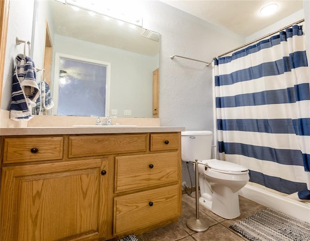 bathroom with tile patterned flooring, vanity, toilet, and walk in shower