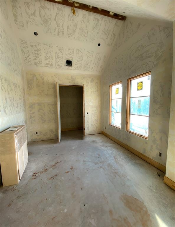 empty room featuring vaulted ceiling with beams