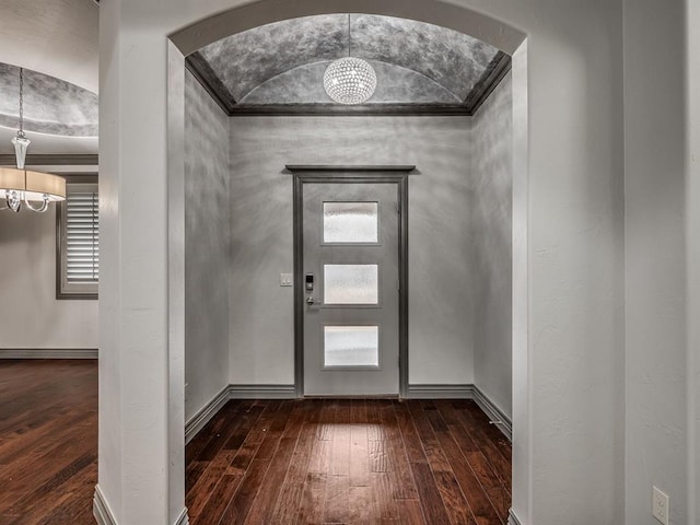 entryway with dark hardwood / wood-style floors, crown molding, and an inviting chandelier