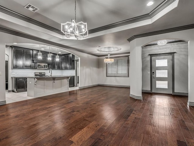 interior space with a tray ceiling, crown molding, wood-type flooring, and an inviting chandelier