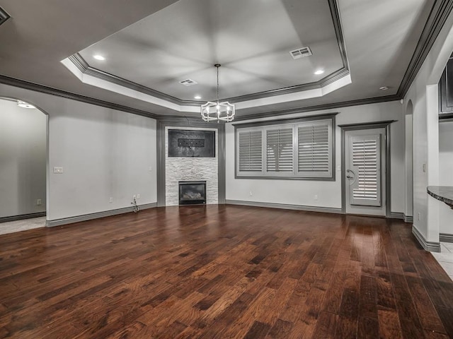 unfurnished living room featuring dark hardwood / wood-style flooring, crown molding, and a tray ceiling