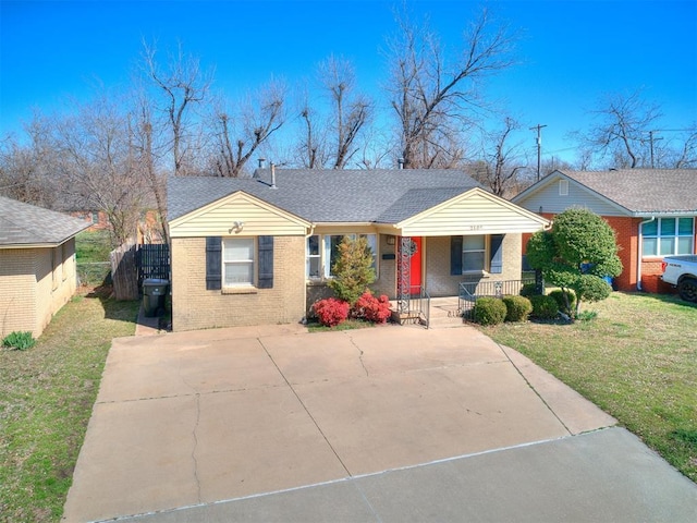 view of front of house with brick siding, covered porch, concrete driveway, and a front lawn