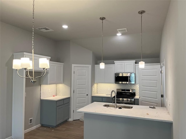 kitchen featuring white cabinetry, stainless steel appliances, dark hardwood / wood-style floors, backsplash, and pendant lighting