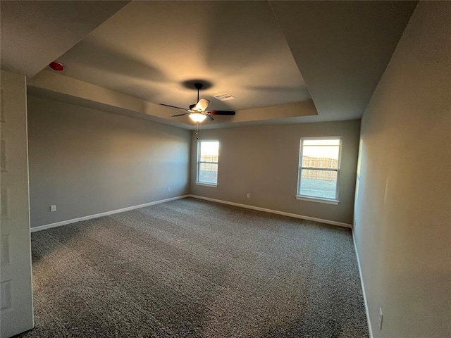 carpeted empty room with a raised ceiling and ceiling fan