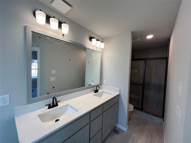 bathroom with vanity, toilet, and a shower with door