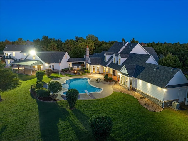 pool at twilight featuring a lawn, cooling unit, and a patio