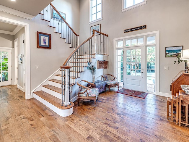 entrance foyer featuring ornamental molding, a healthy amount of sunlight, a high ceiling, and hardwood / wood-style flooring