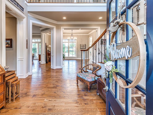 entryway with hardwood / wood-style flooring, crown molding, and a chandelier