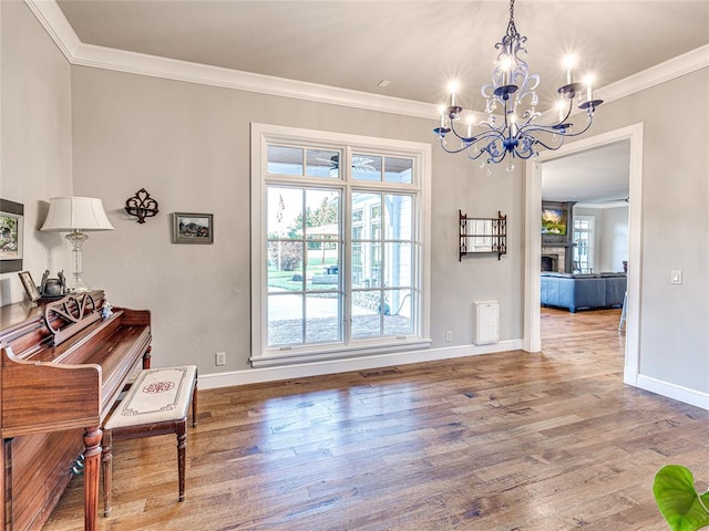 dining area featuring a chandelier, wood-type flooring, a stone fireplace, and crown molding