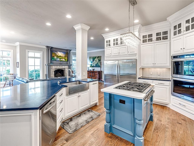 kitchen with pendant lighting, sink, an island with sink, appliances with stainless steel finishes, and white cabinetry