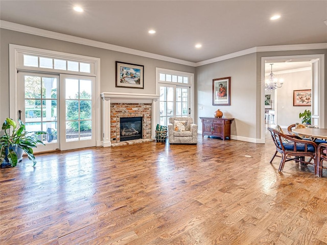 living room featuring crown molding, a fireplace, an inviting chandelier, and hardwood / wood-style flooring