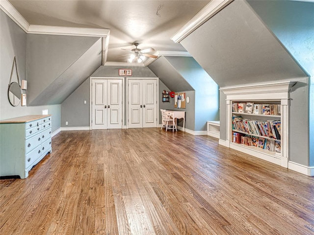 additional living space with built in shelves, ceiling fan, lofted ceiling, and hardwood / wood-style flooring