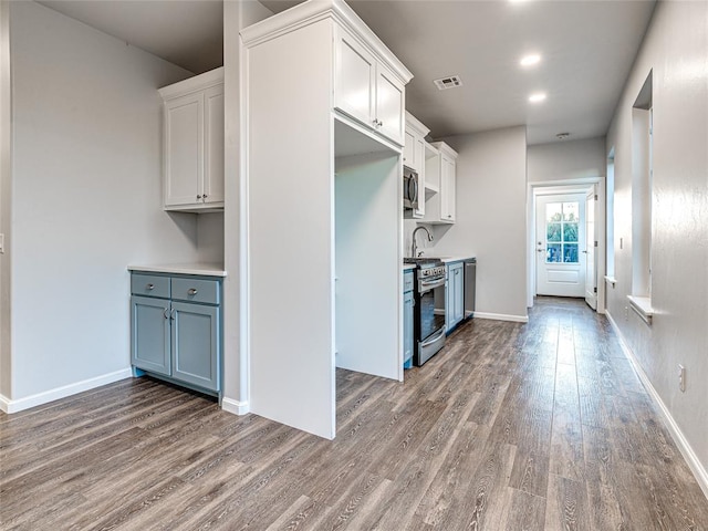 kitchen featuring hardwood / wood-style flooring, white cabinets, and appliances with stainless steel finishes