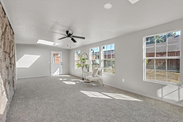 unfurnished room featuring carpet floors, a skylight, and ceiling fan