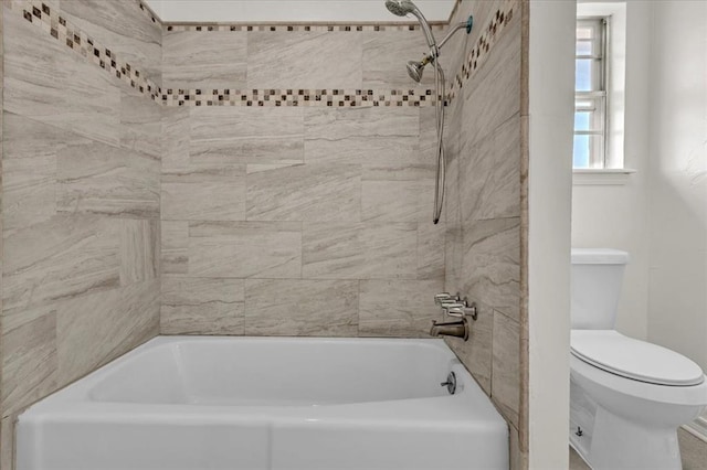 bathroom featuring tiled shower / bath combo and toilet