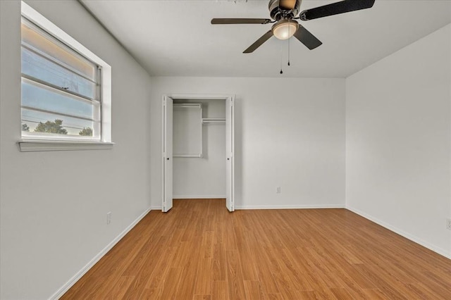 unfurnished bedroom featuring ceiling fan, light hardwood / wood-style floors, and a closet