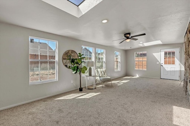 interior space featuring vaulted ceiling with skylight, ceiling fan, plenty of natural light, and light carpet