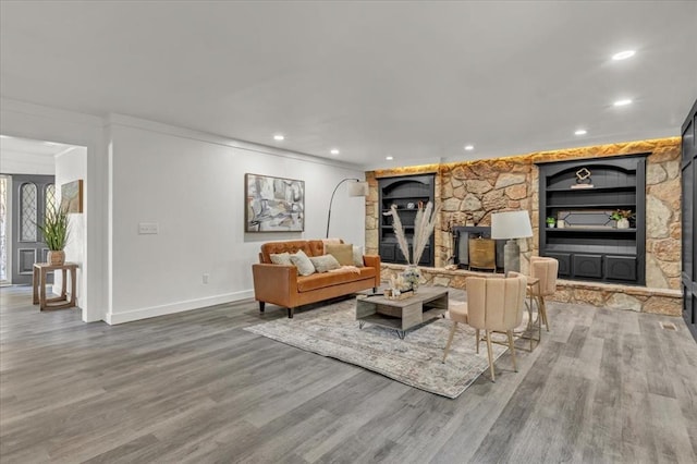 living room featuring hardwood / wood-style flooring, built in features, and ornamental molding