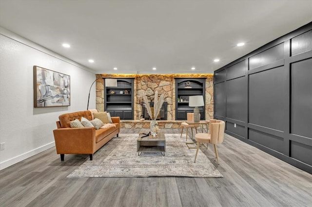 living room with a fireplace, built in features, and light wood-type flooring