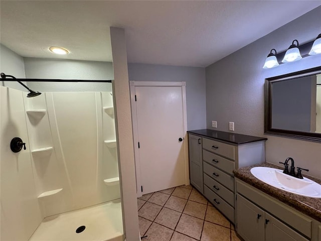 bathroom with tile patterned flooring, vanity, and walk in shower