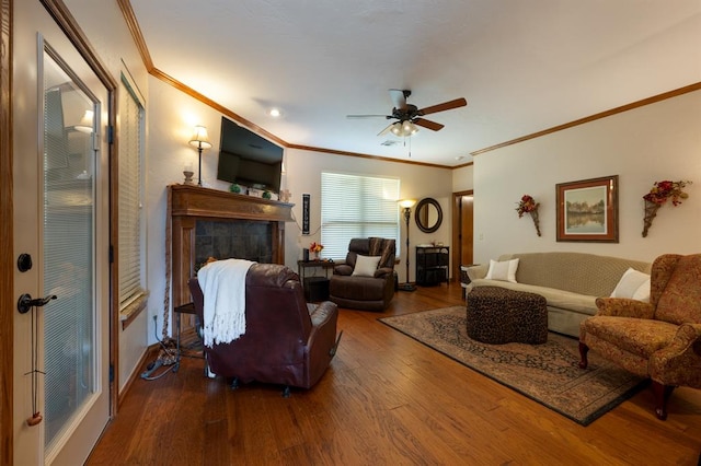 living room featuring a tile fireplace, crown molding, hardwood / wood-style floors, and ceiling fan