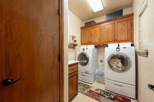 laundry room with cabinets, light tile patterned floors, a textured ceiling, and separate washer and dryer